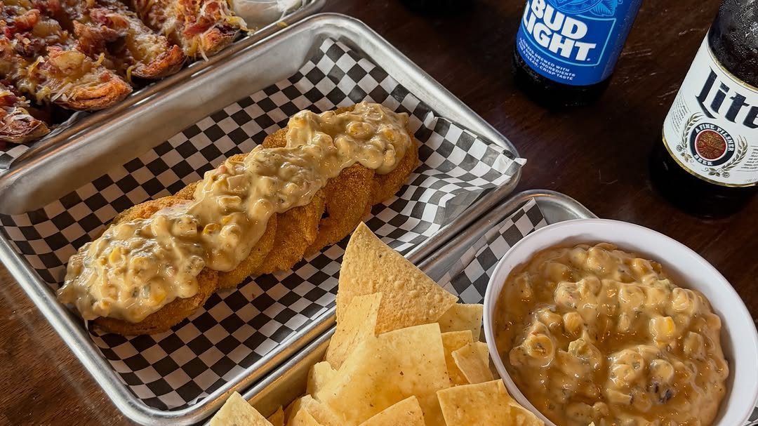 Fried green tomatoes, loaded potato bites and chips with dip next to cold beers at Trussville Social